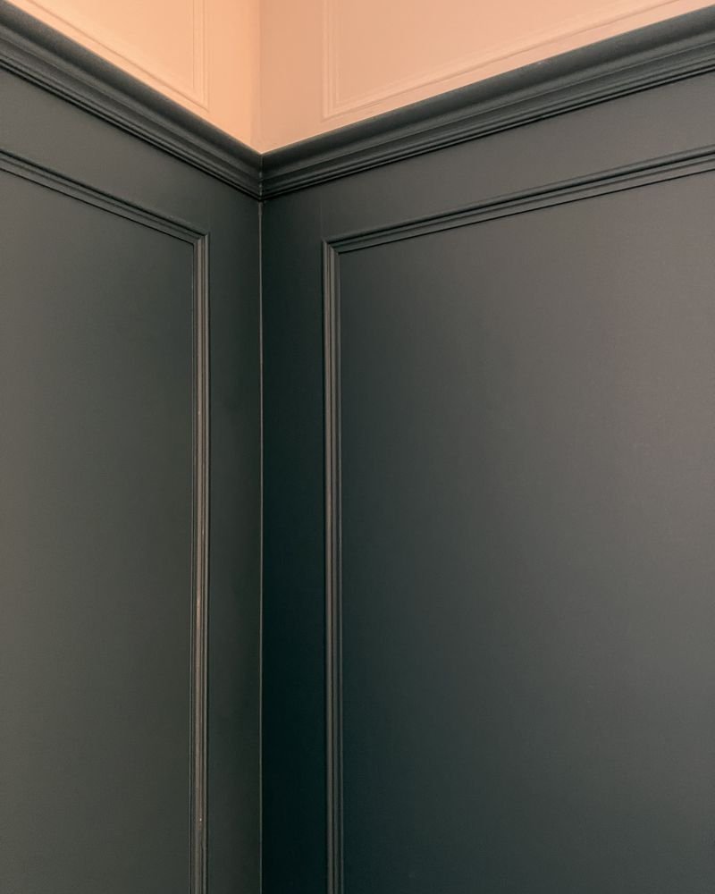 Deep teal wall panelling meeting a soft pink ceiling