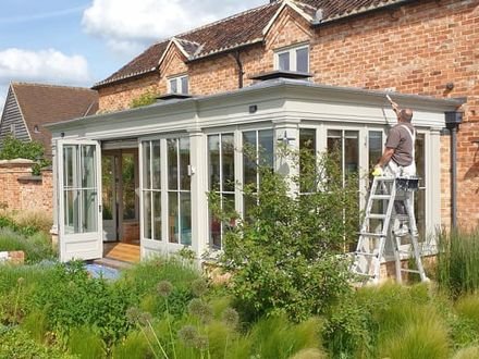 Exterior painting in progress on a brick house and orangery