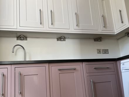 A kitchen hand-painted in dusty pink with cream wall units