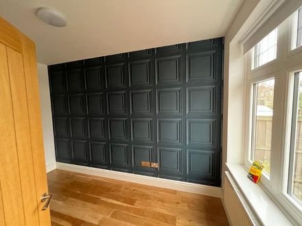 A feature wall papered in a dark raised-panel design