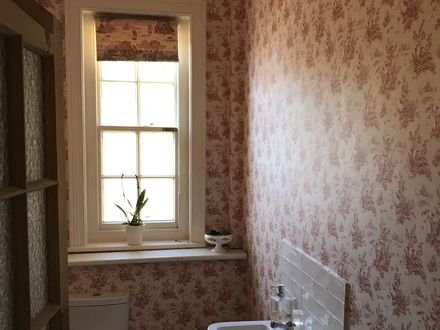 A cloakroom papered in a red toile pattern
